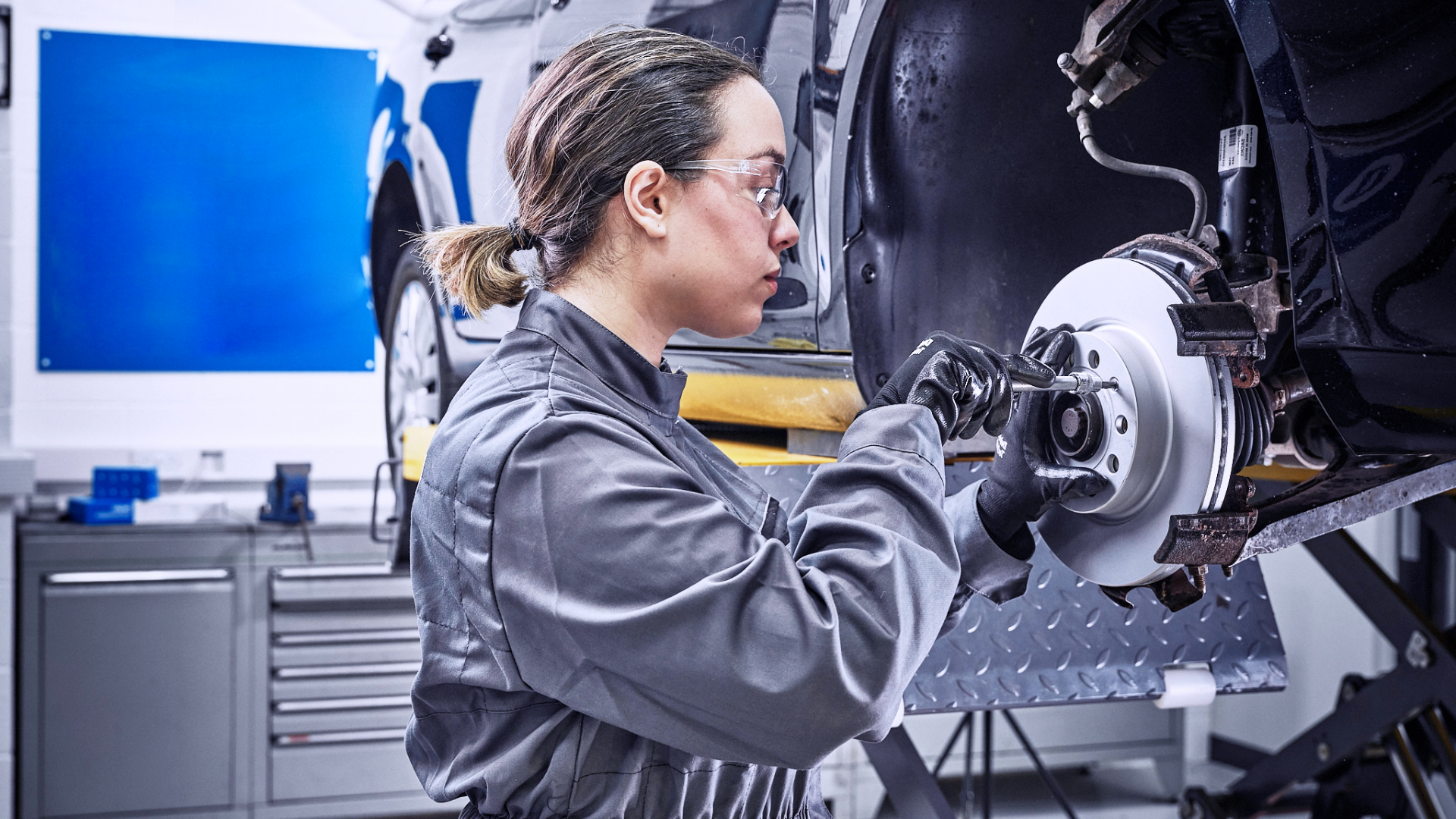 Delphi Technologies Expert replacing the front disks and brake pads of a raised vehicle.