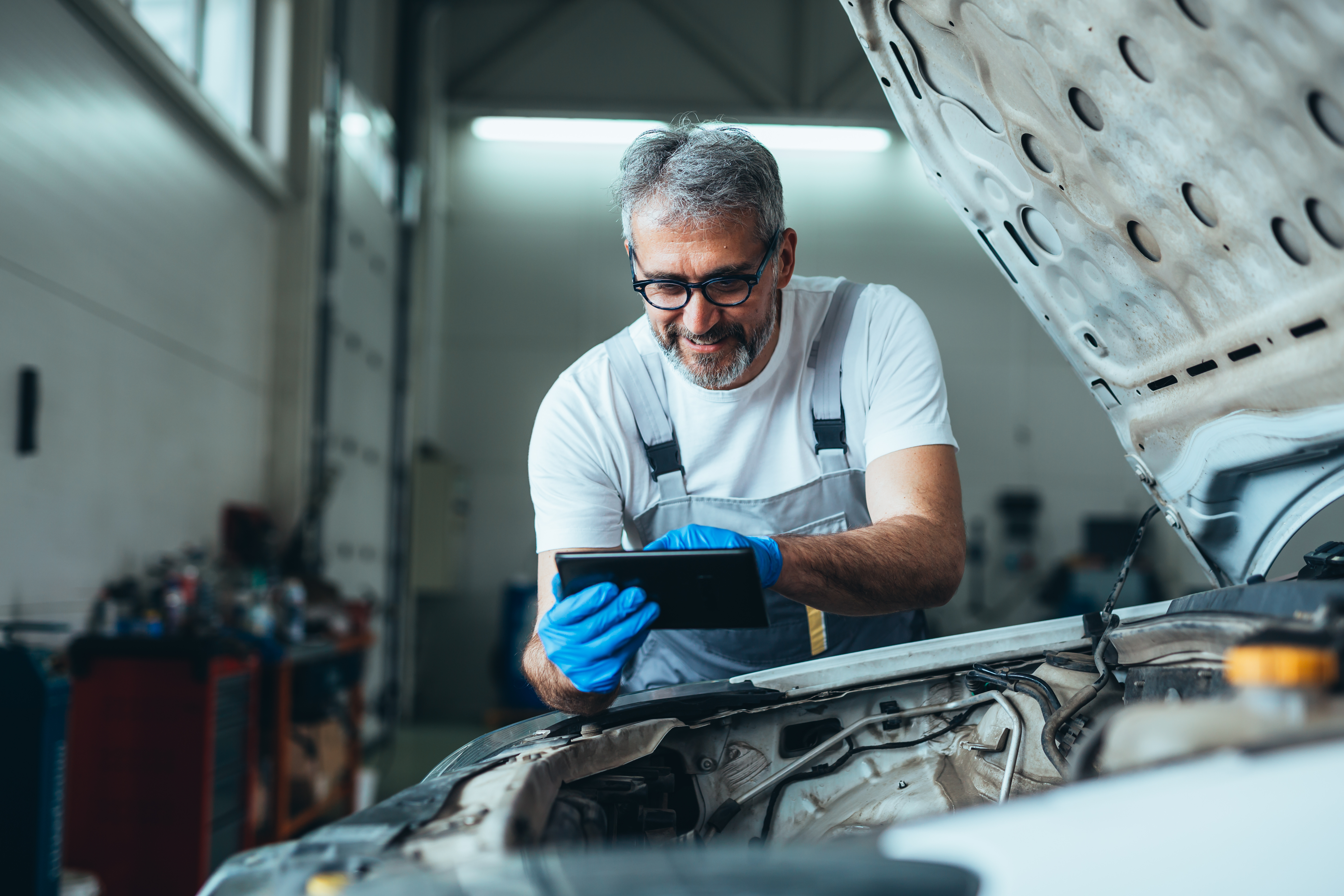 Technicians from across Europe use The Delphi Academy Delphi Technologies expert using a laptop which is resting on top of the exposed engine of a vehicle.